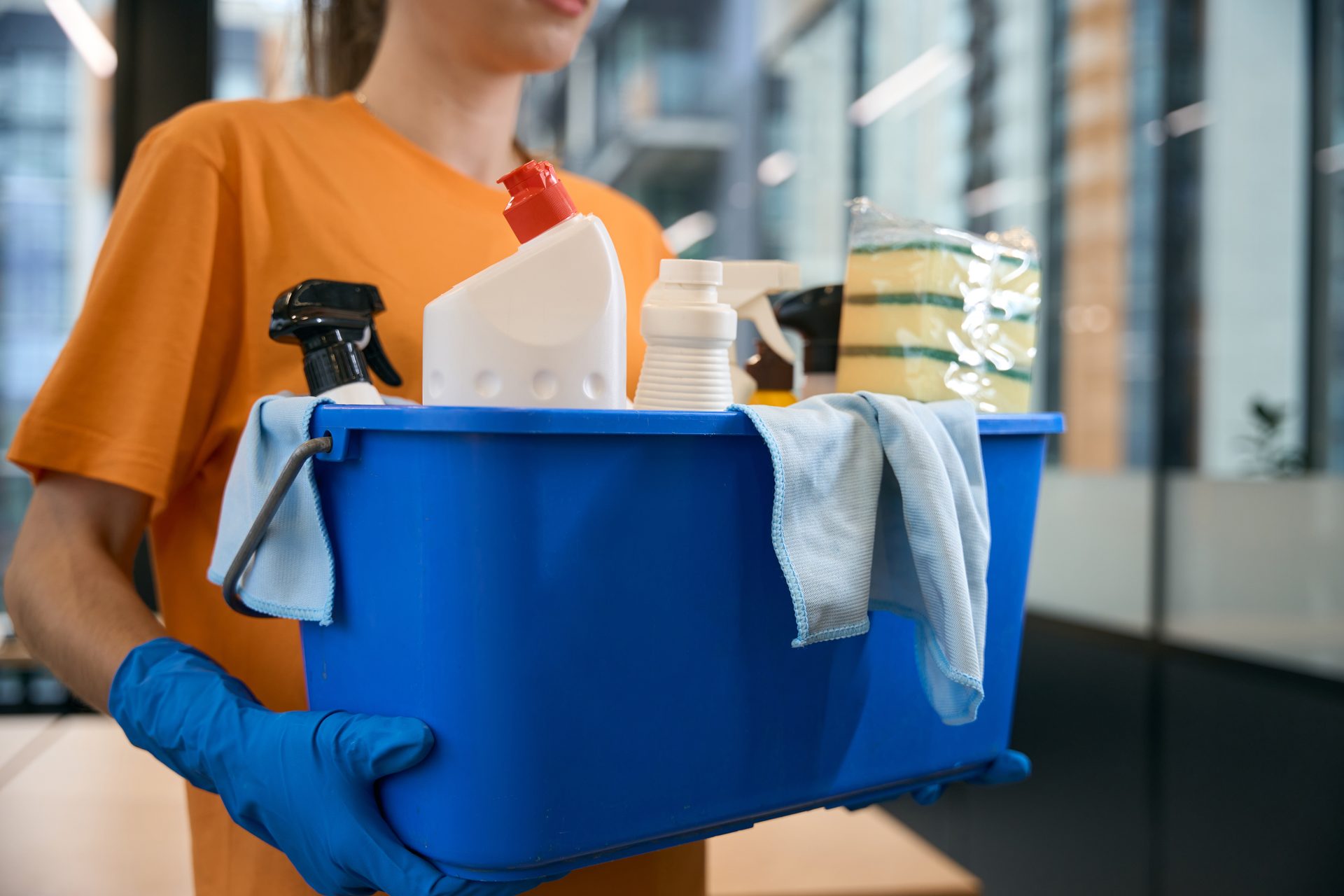 Schoonmaker draagt een emmer met schoonmaakmiddelen